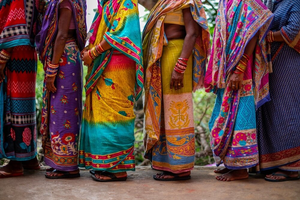 Women's legs standing in line wearing colorful clothing.