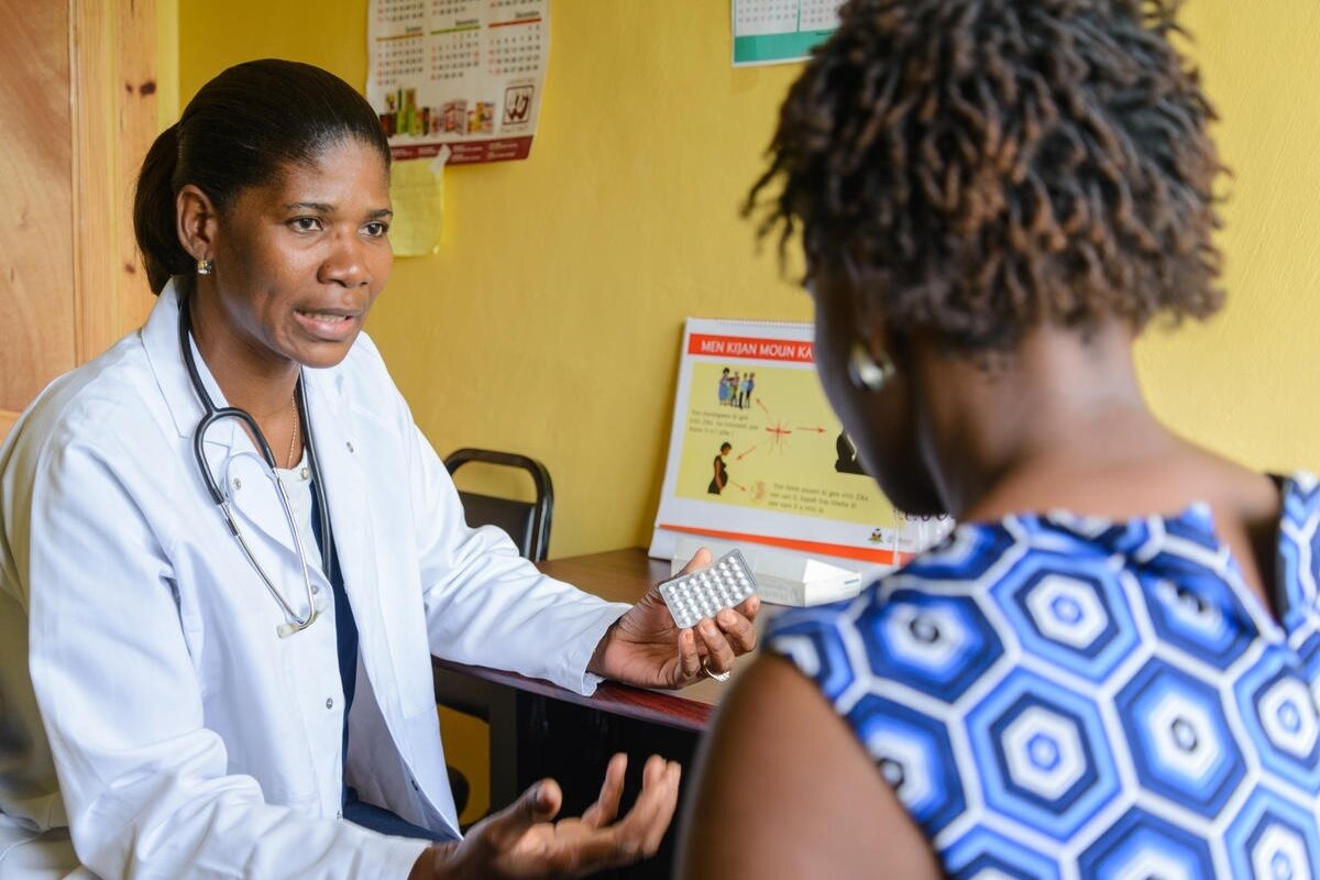 A doctor shows a package of pills to a patient.