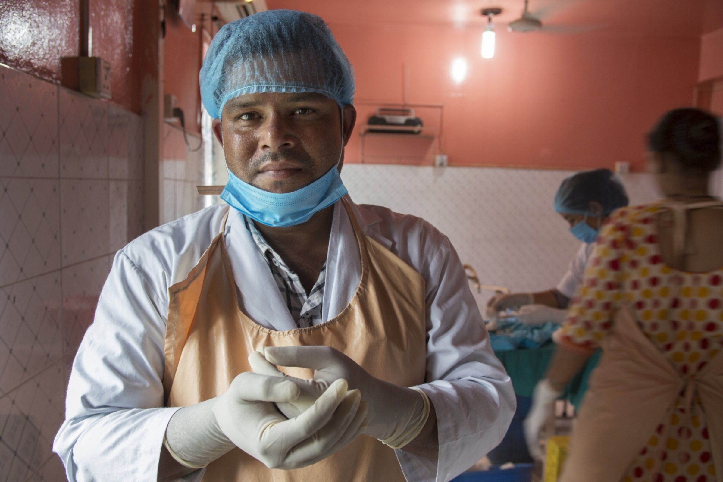 Doctor wears scrubs and look at camera in an operating room.