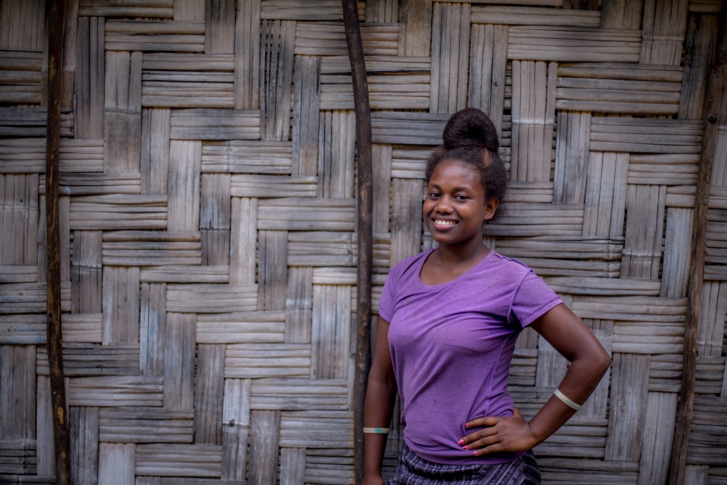 A 15-year-old girl smiles in a purple t-shirt, with her hand on her hip.