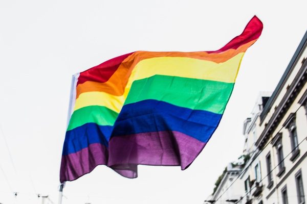 A rainbow flag flies over a city.